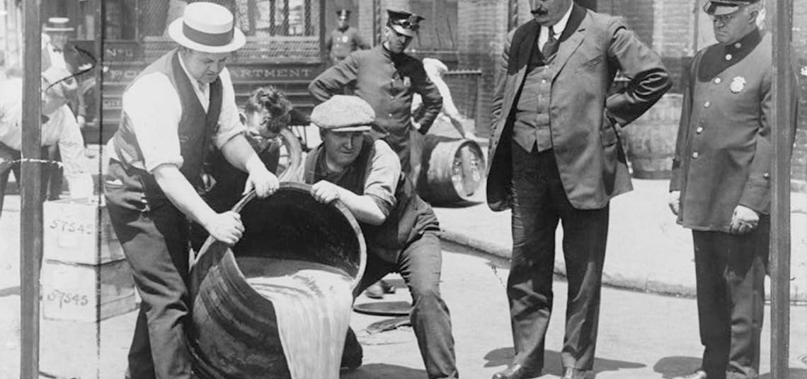 Ley seca. Hombres tirando el contenido de un barril lleno de alcohol