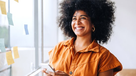 Mujer sonriendo con un móvil en la mano