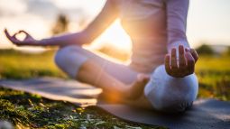 Persona meditando en un parque durante el amanecer