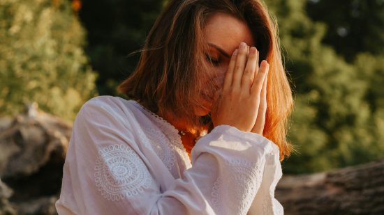 Mujer rezando cerca de un bosque