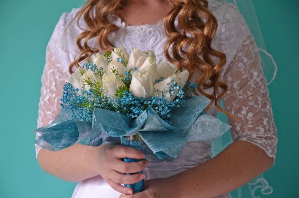Novia sosteniendo un ramo de rosas blancas