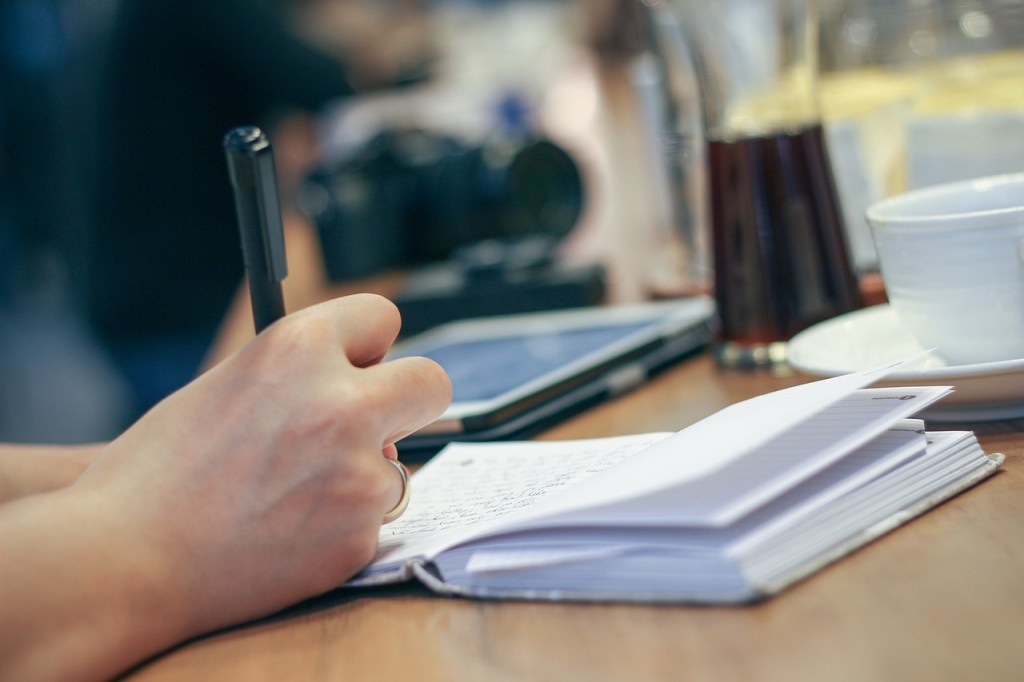 Persona escribiendo con un bolígrafo en un cuaderno