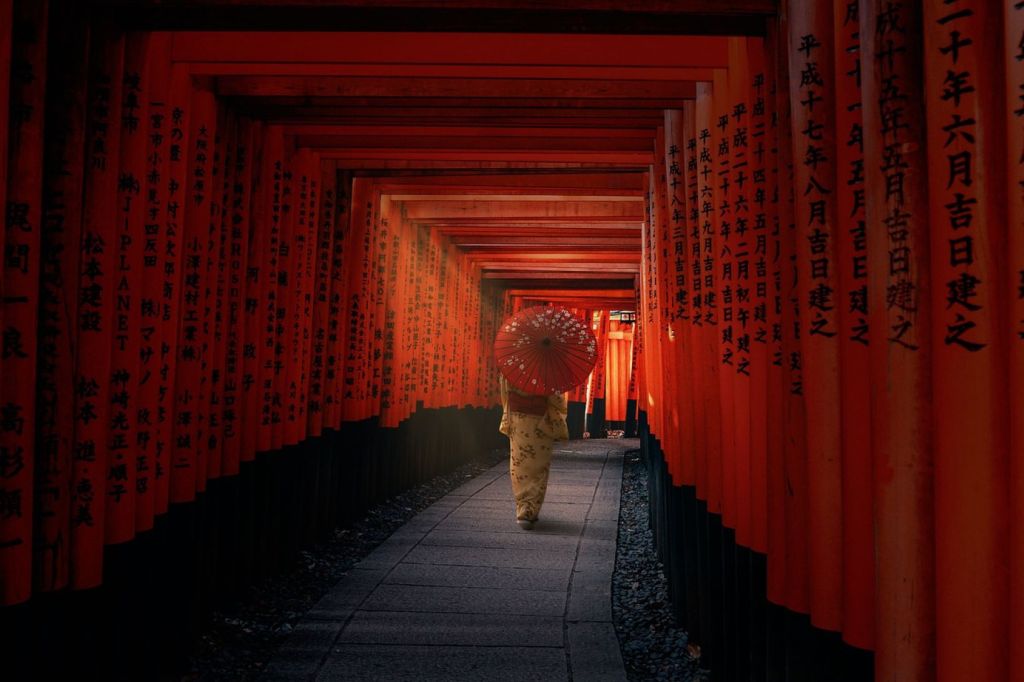 Mujer japonesa que camina vestida con kimono y sombrilla